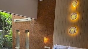 A modern bedroom with a bed, bedside tables, a small bedside lamp, and a view of a swimming pool. - Grange Boutique Siem Reap (Siem Reap)