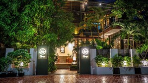 A hotel entrance with a neon sign, a staircase, and potted plants. - Grange Boutique Siem Reap (Siem Reap)