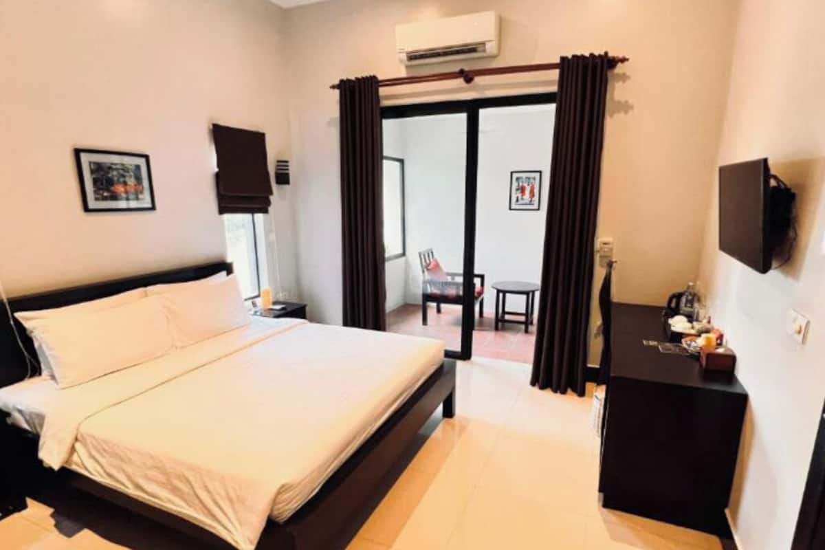 A hotel room with a bed, a desk, a chair, and a television.