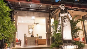 A statue, reception desk, and indoor plants in a well-lit lobby area. - Grange Boutique Siem Reap (Siem Reap)