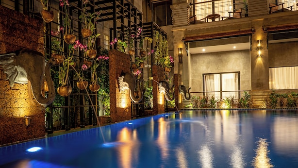 A swimming pool with a brick wall and hanging planters. - Grange Boutique Siem Reap (Siem Reap)