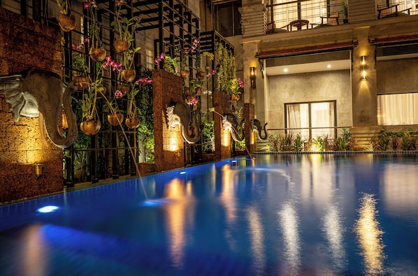 A swimming pool with a brick wall and hanging planters.