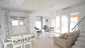 Een ruime woonkamer met een eettafel, stoelen, een bank en een trap.