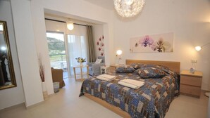 Een slaapkamer met een groot bed, nachtkastje, een stoel, een tafel met een bloemenvaas en uitzicht op de omgeving.