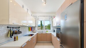 Een moderne keuken met houten kastjes, een roestvrijstalen koelkast en een raam met gordijnen.