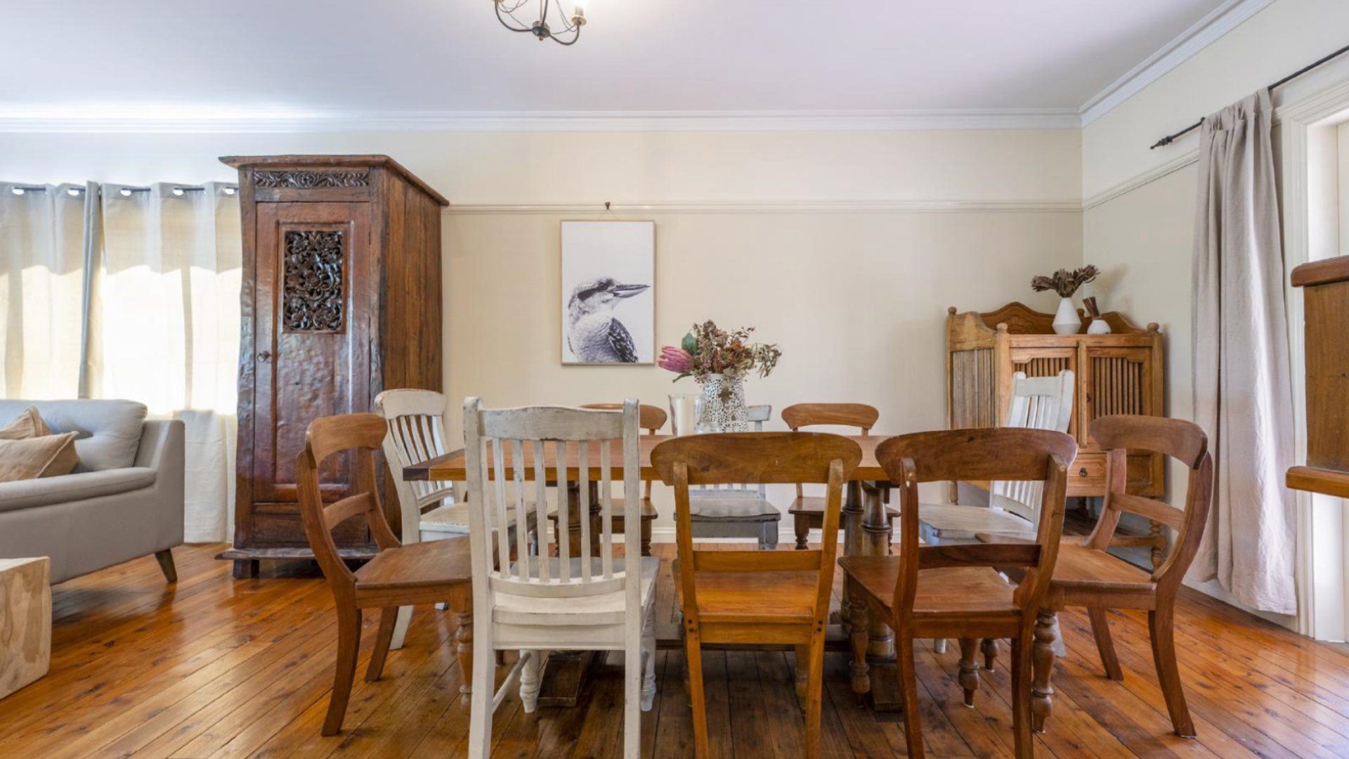 Un coin repas avec une table et des chaises en bois, un buffet blanc et un tableau accroché au mur.