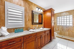 Un baño con un tocador amplio, un espejo, una ventana con vistas y una zona de ducha.