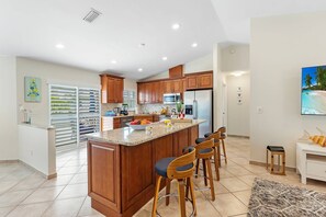 Una cocina moderna con una isla central, armarios de madera y una zona de bar con taburetes.