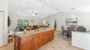 A spacious kitchen with a large island, wooden cabinets, and a dining area with a table and chairs. - Private Pool｜Near Beach｜Fenced Yard｜Outdoor Living (Naples)