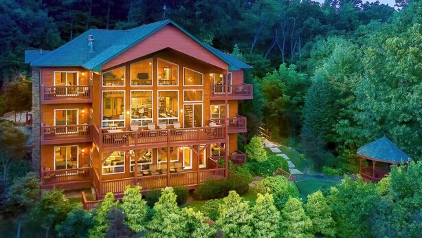 Ein großes, mehrstöckiges Chalet mit Balkonen und großen Fenstern, umgeben von dichtem Wald.