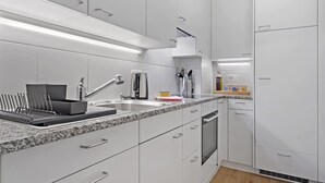 Una cocina moderna con armarios blancos, encimera de granito y suelo de madera.