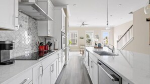 Uma cozinha moderna com armários brancos, painel de parede em mármore e uma ilha central com pia.