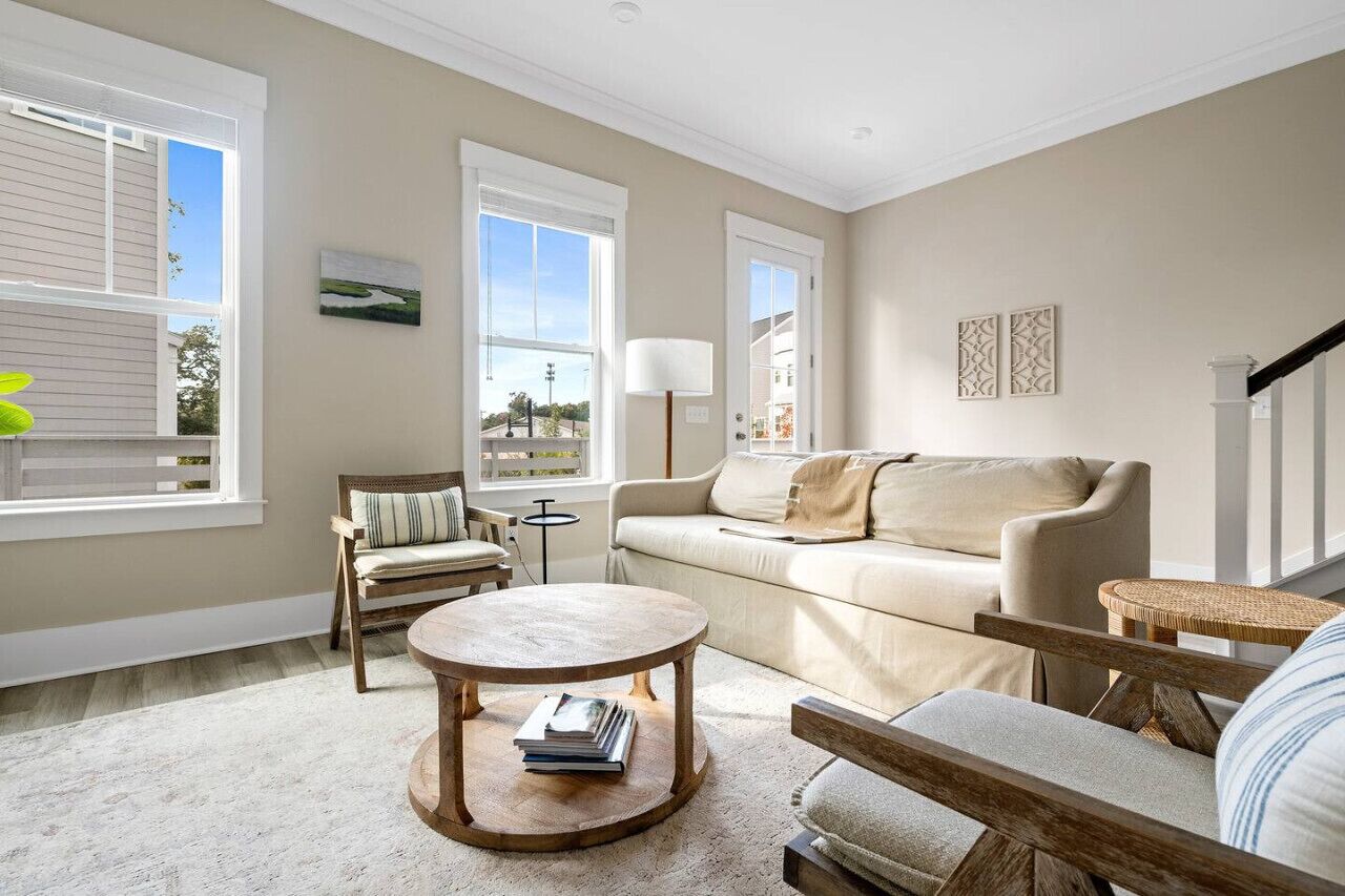A living room with a beige sofa, a round coffee table, and a wicker chair.