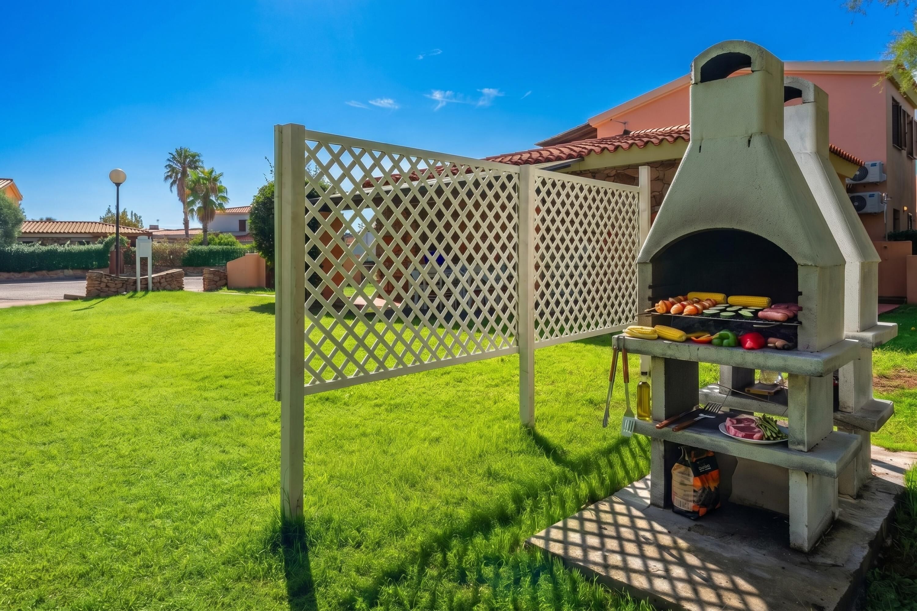 A backyard with a brick barbecue grill and a wooden fence.