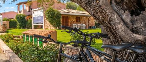 A residential area with a stone building, a large tree, and a bicycle.