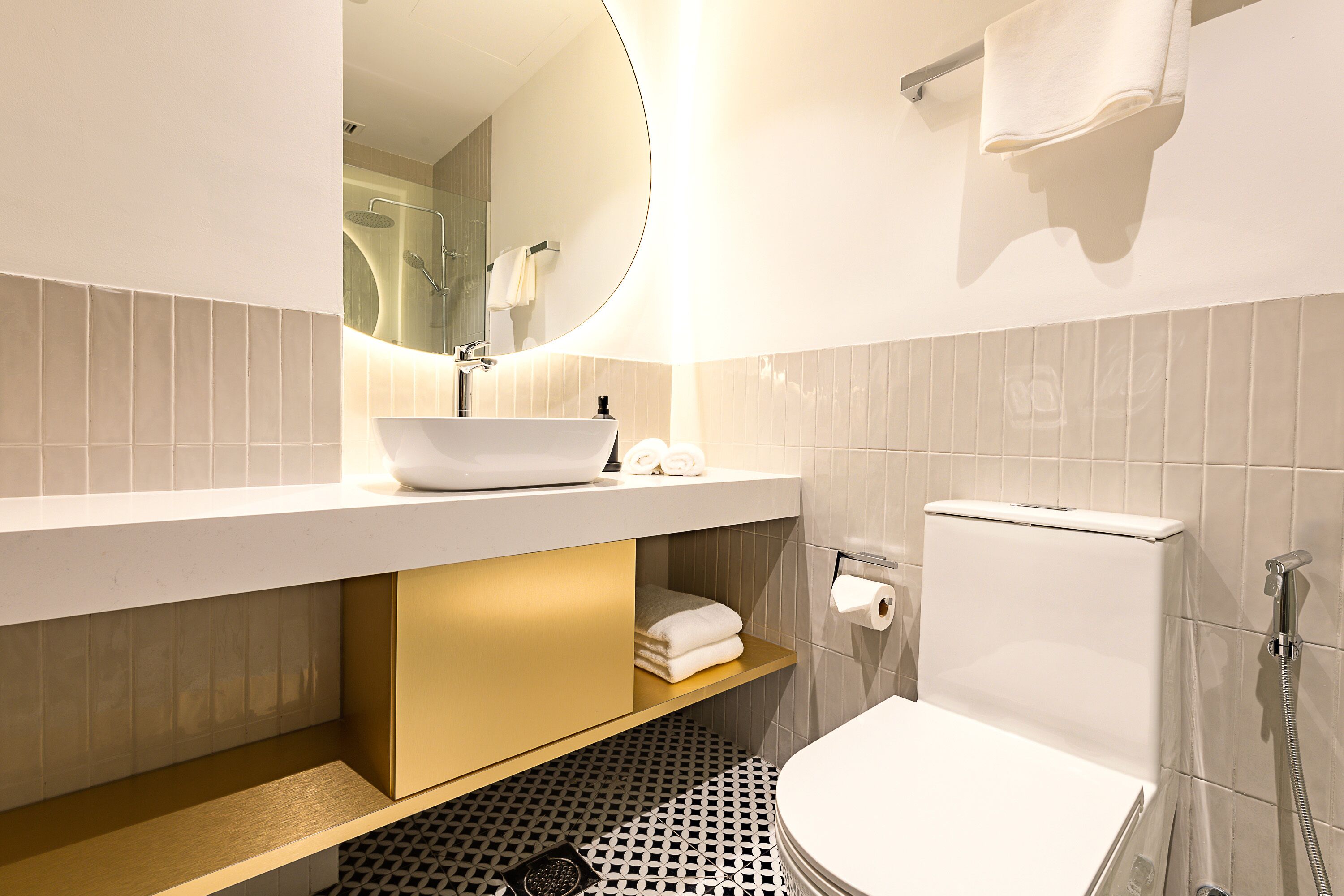 A modern bathroom with a white sink, gold cabinet, and a toilet.