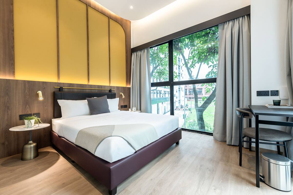 Een moderne hotelkamer met een groot bed, een bureau en uitzicht op de omgeving.