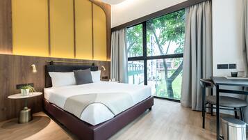 Una habitación de hotel moderna con una cama grande, un escritorio y vistas al exterior.