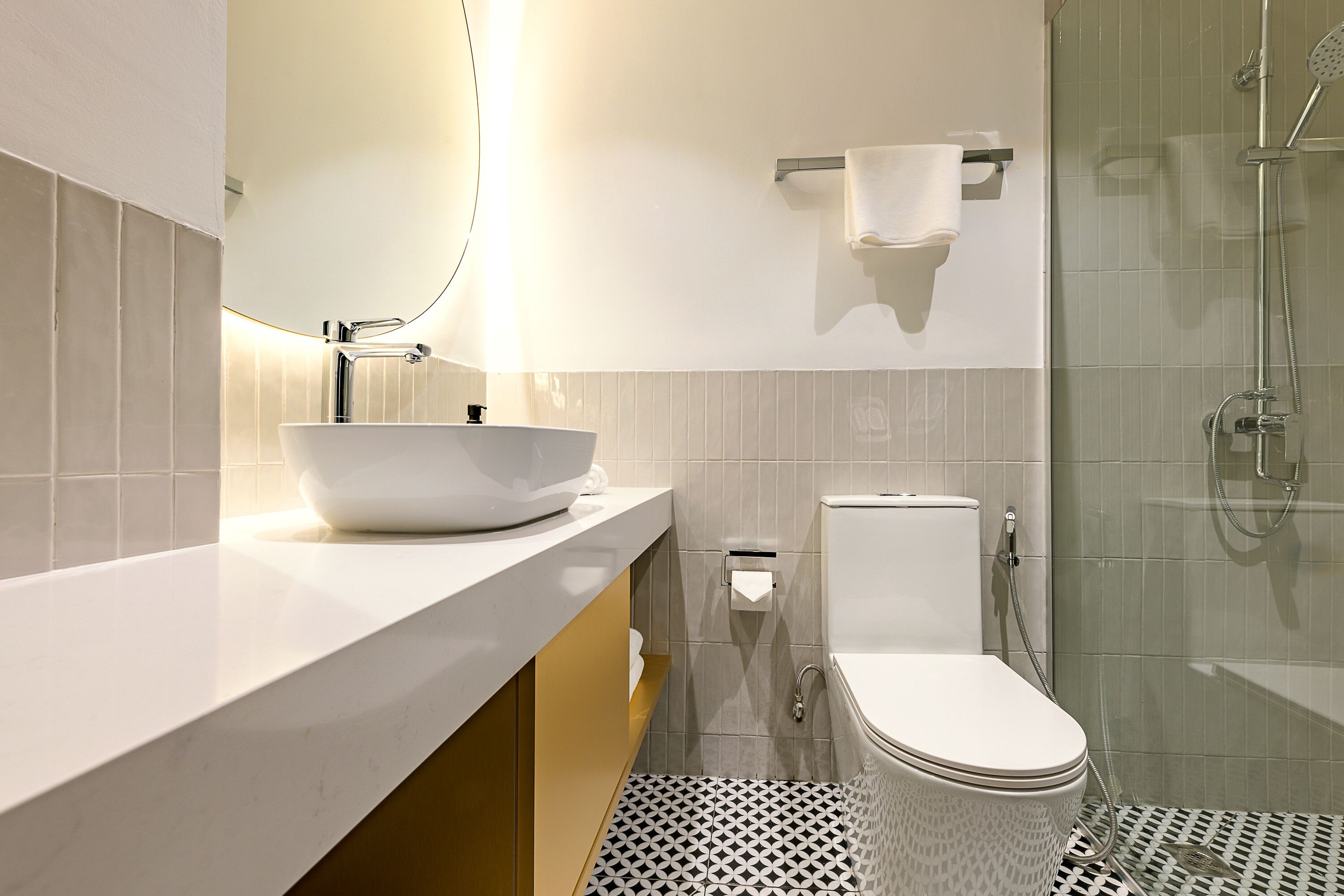 Une salle de bain moderne avec un lavabo, des toilettes et une douche, le tout de couleur blanche.