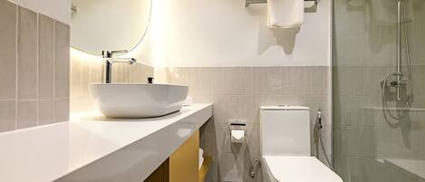 A modern bathroom with a white sink, toilet, and shower.