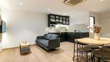 Una cocina moderna con un sofá gris, una mesita auxiliar pequeña y una mesa de comedor redonda con taburetes.