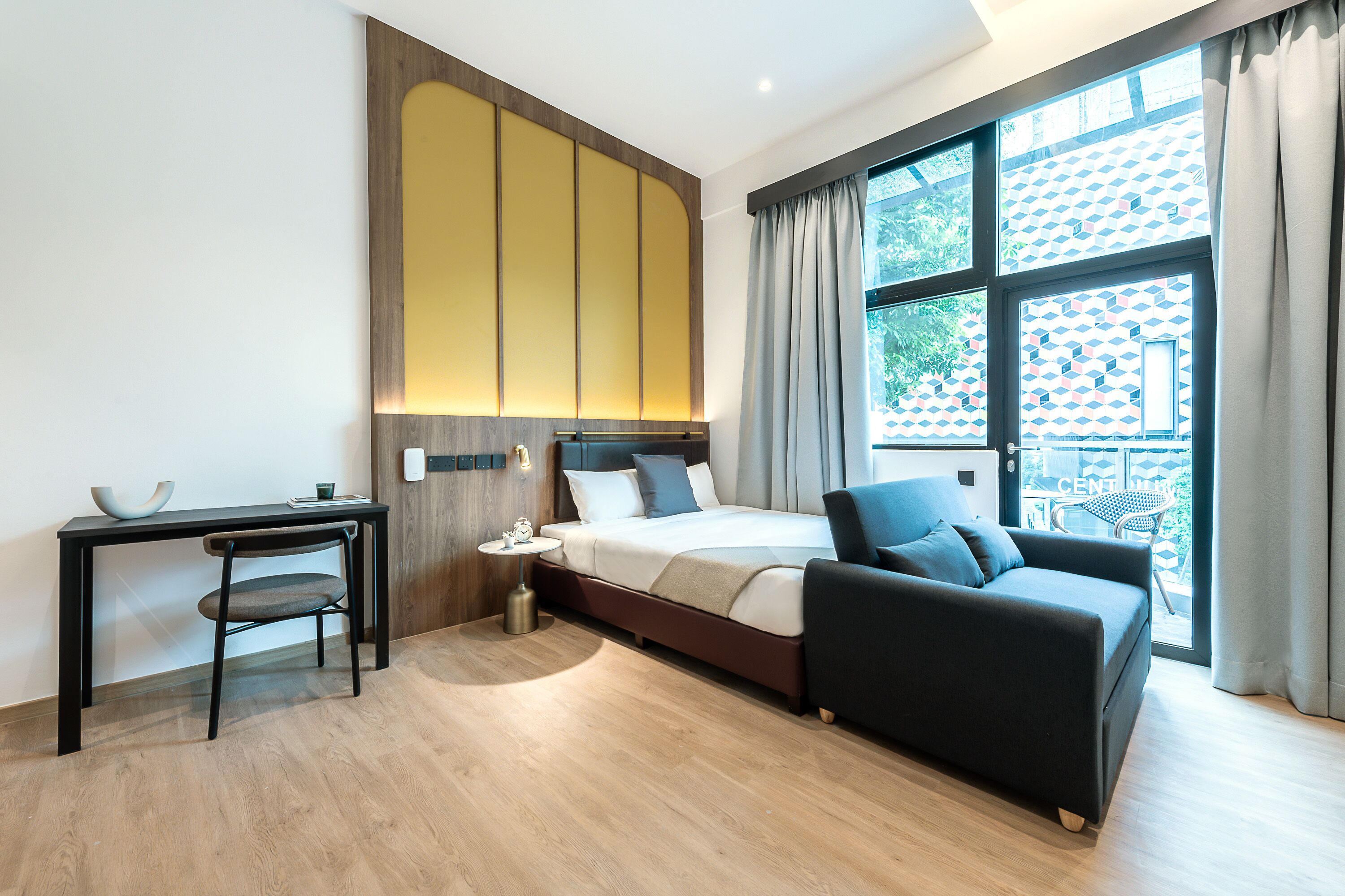 Ein modernes Hotelzimmer mit Bett, Schreibtisch, Stuhl und Sofa.