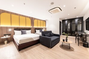 Una habitación de hotel moderna con una cama grande, un sofá, una mesita redonda y una zona de escritorio.