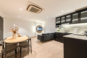 Una cocina moderna con una isla central, armarios oscuros y un televisor de pantalla plana montado en la pared.