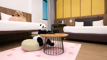 A hotel room with two beds, a round coffee table, and a panda plush toy.
