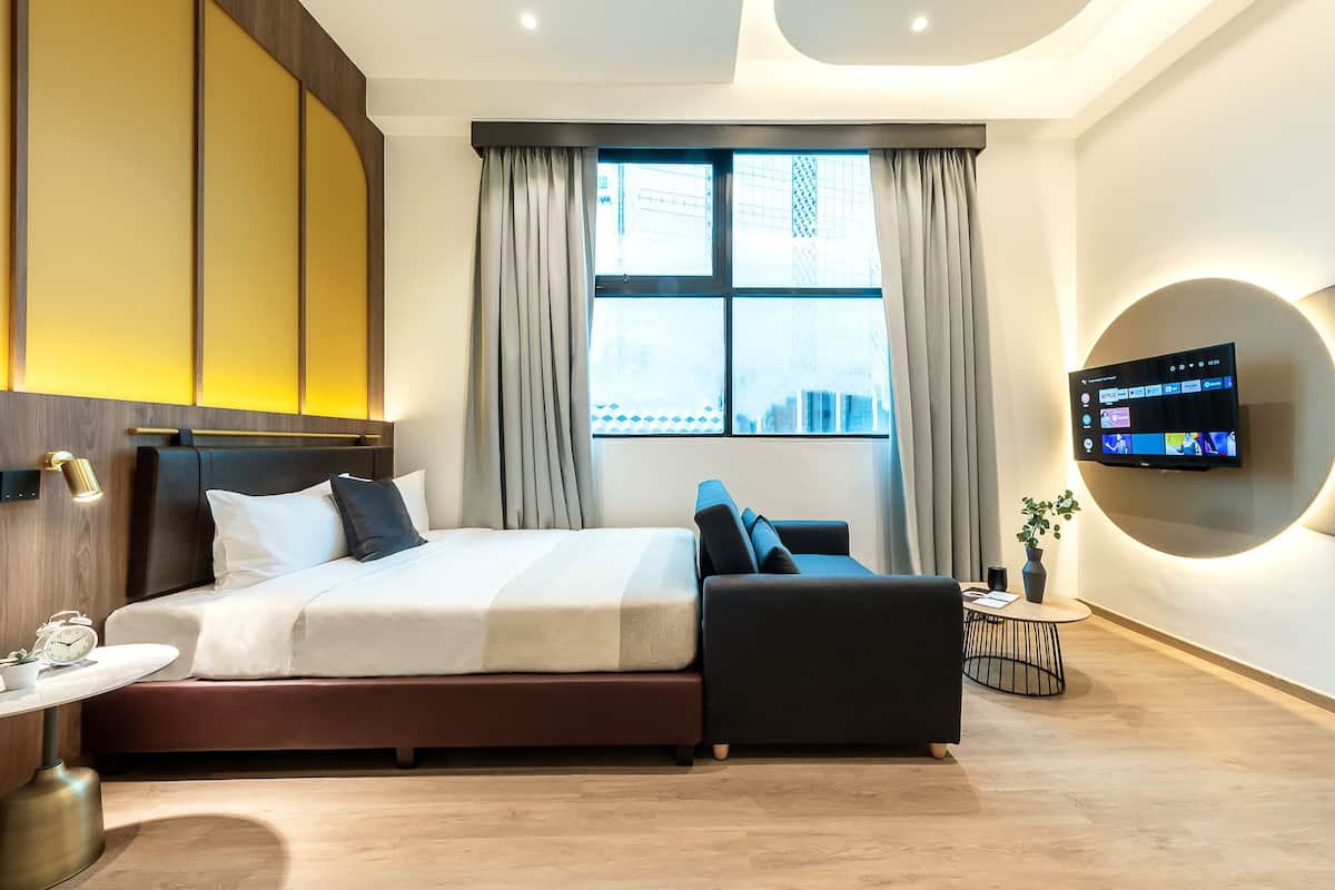 Een moderne hotelkamer met een bed, nachtkastje, televisie en uitzicht op de stad.