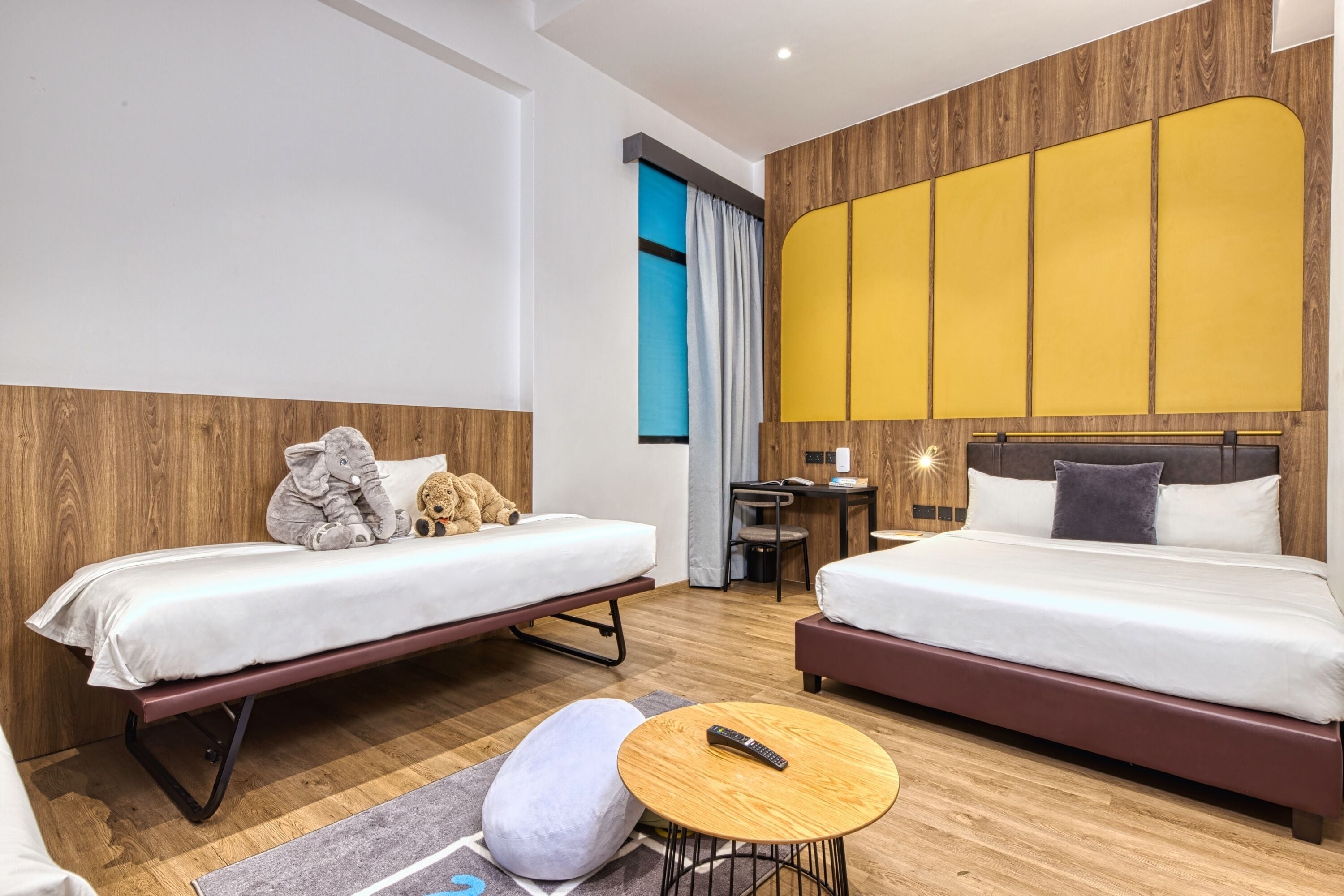 Ein Hotelzimmer mit zwei Betten, einem Schreibtisch und einem kleinen runden Tisch.