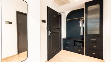 A modern bedroom with a dark wardrobe, a mirror, and a built-in safe.