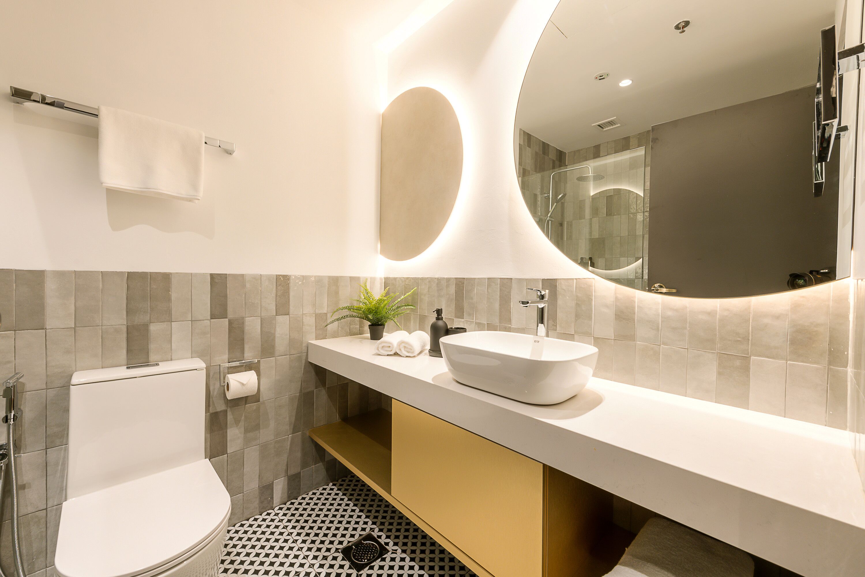 Une salle de bain moderne équipée de toilettes, d’un lavabo, d’un miroir et d’une douche.