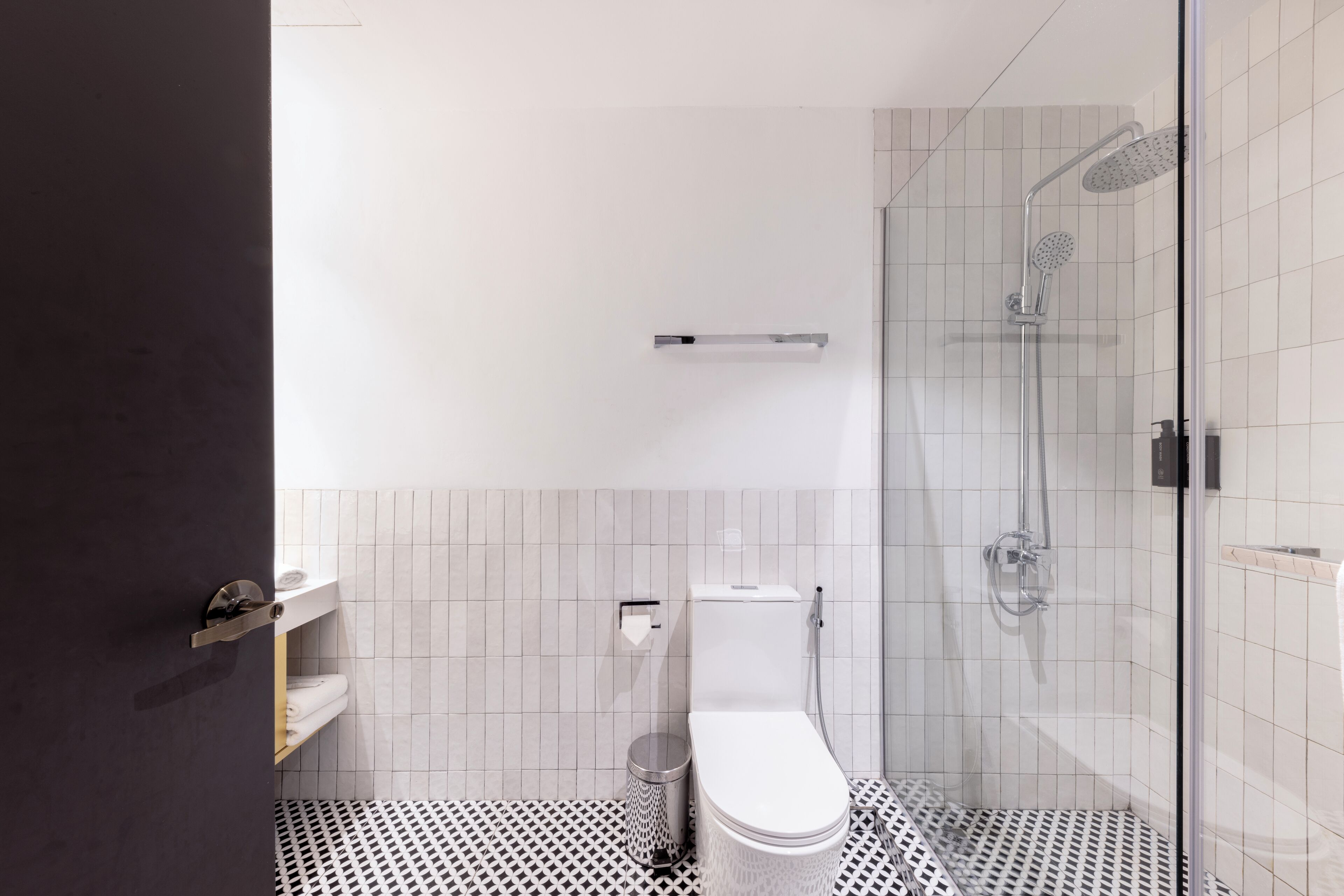 A modern bathroom with a toilet, a shower, and a glass-enclosed shower area.
