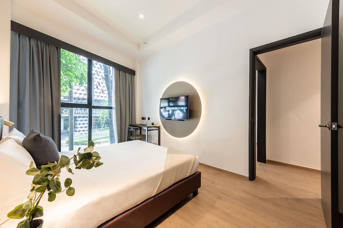Een moderne hotelkamer met een groot bed, een aan de muur bevestigde televisie en uitzicht op het landschap.