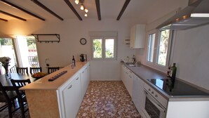 A kitchen with a central island, white cabinets, a stove, and a window. - Charming detached holiday home with private pool–close to beach and fully fenced (Dénia)