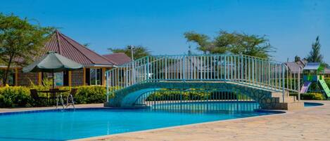 A swimming pool with a bridge, a gazebo, and a playground.