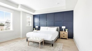 Ein modernes Schlafzimmer mit einem großen Bett, einem Nachttisch und einer Bank.