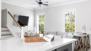 Eine moderne Küche mit weißer Arbeitsplatte, Deckenventilator und großem Fenster.