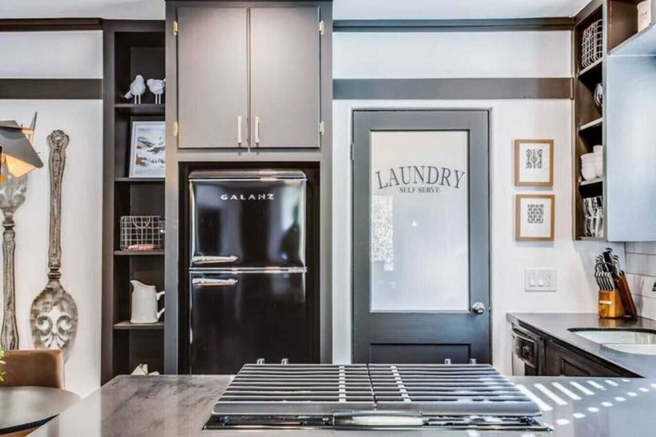Una cocina moderna con un refrigerador de acero inoxidable integrado, una puerta de lavandería autoservicio y una encimera de mármol.