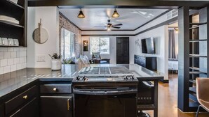 Een moderne keuken met een centraal eiland, zwarte kastjes en een plafondventilator.