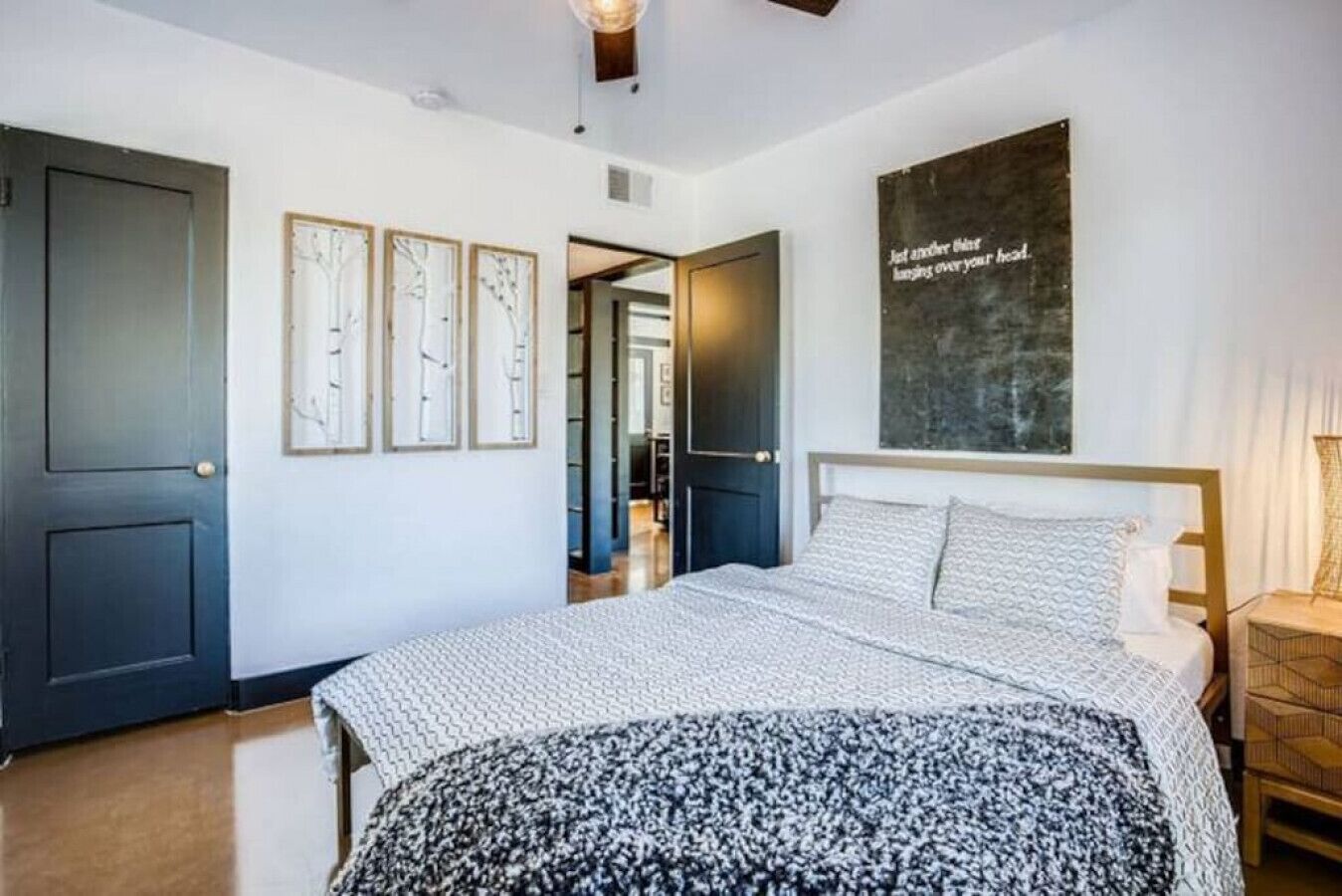 Une chambre à coucher avec un lit, une grande œuvre d’art murale et une porte.