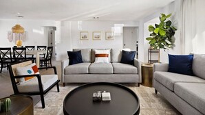 A modern living room with a grey sofa, black armchairs, a round coffee table, and a dining area with a table and chairs. - The Minnezona Modern-Old Town (Scottsdale)