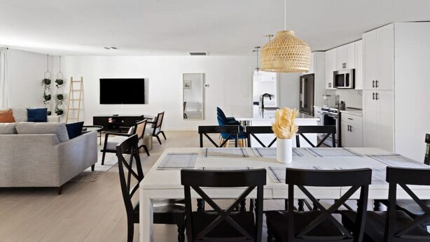 A modern living room with a sofa, TV, and dining area with chairs and a table. - The Minnezona Modern-Old Town (Scottsdale)