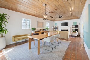 Un vaste espace de vie doté d’un plafond en bois, d’une table à manger et d’un canapé.