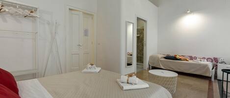 Una habitación de hotel con una cama grande, un sofá cama, una mesita redonda y un armario.