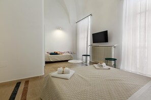 A modern hotel room with a large bed, a flat-screen TV mounted on the wall, and a small seating area with a table and chairs. - 3141 B&b Incentro Comfort Suite - Central Suite by Barbarhouse (Lecce)