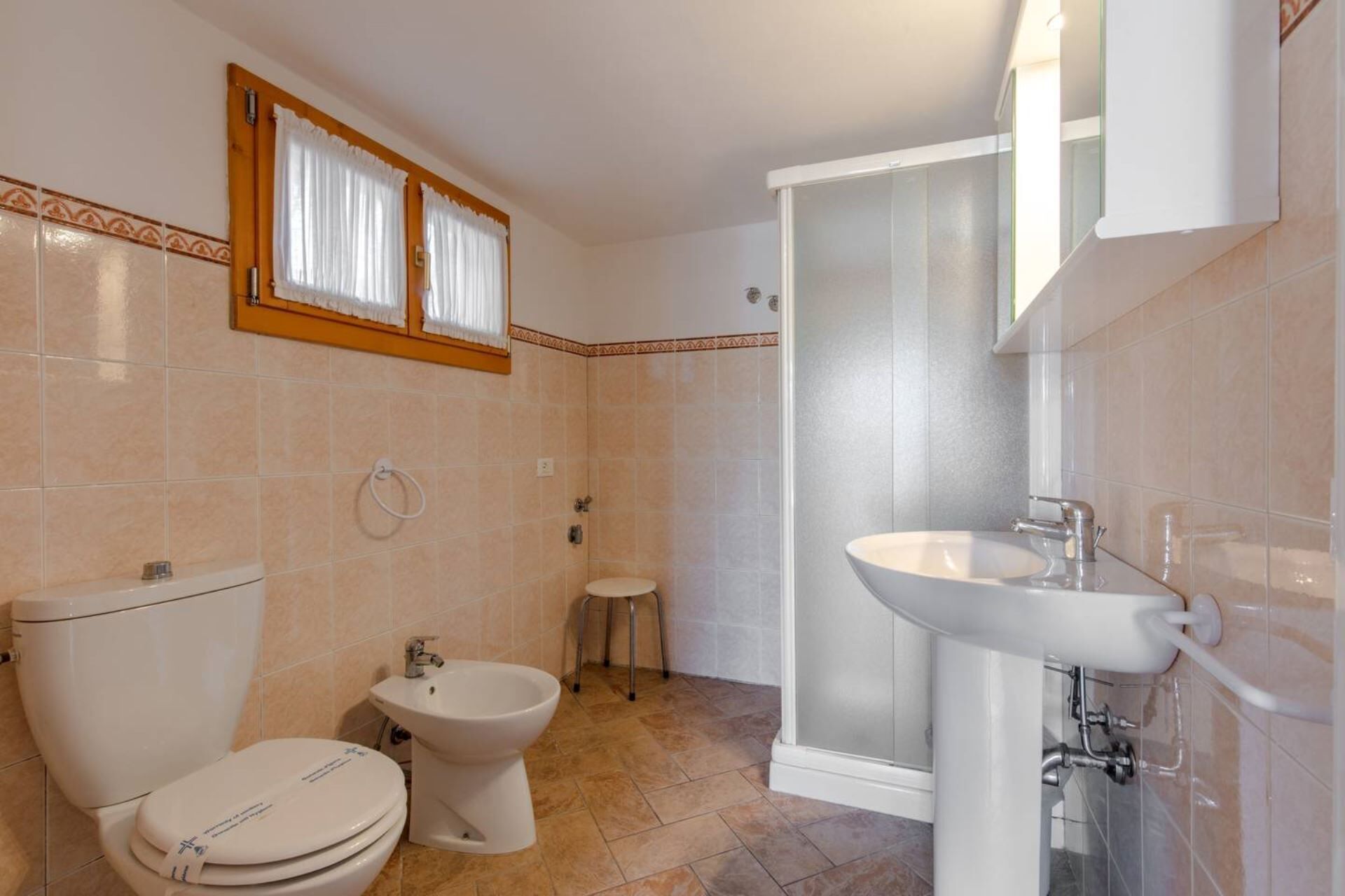 A bathroom with a toilet, bidet, sink, and shower.