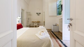 Une chambre d’hôtel équipée d’un lit, d’un bureau, d’une chaise, d’un radiateur et d’une fenêtre donnant sur un paysage verdoyant.
