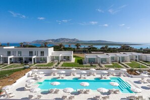 Un moderno resort con zona de piscina, mobiliario exterior y vistas al mar.